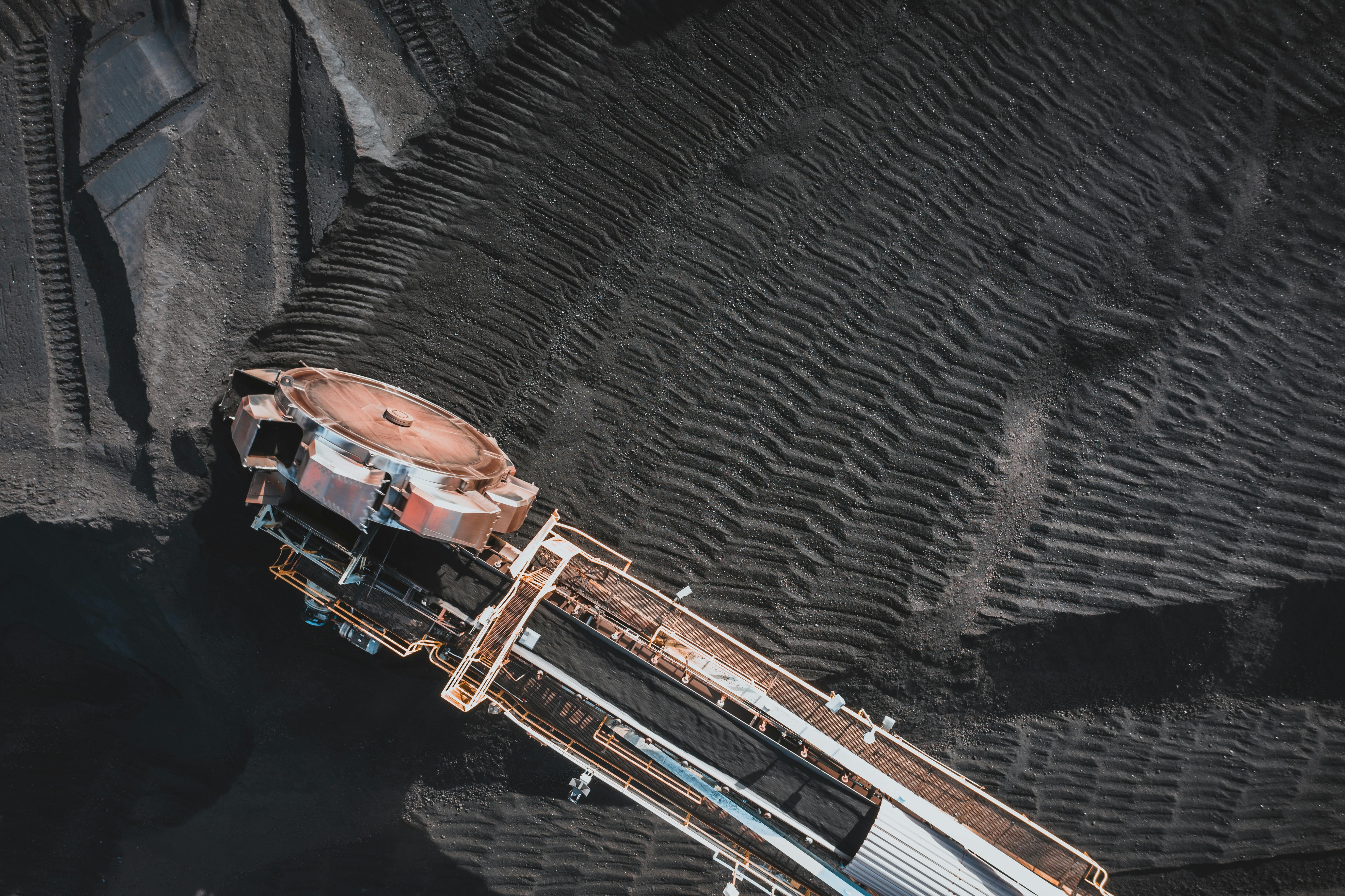 Close aerial view of coal reclaiming equipment operating over a dark stockpile